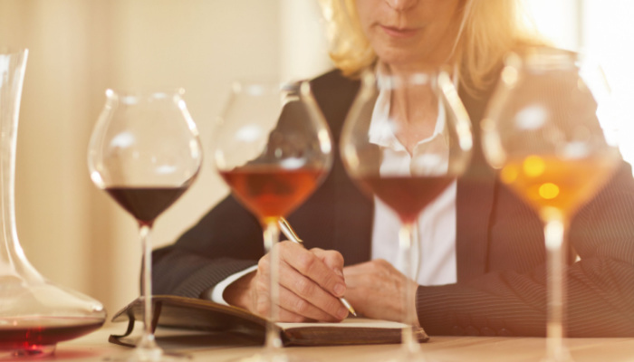 Woman on a coat taking notes during tasting session with different wine and wine glasses in row