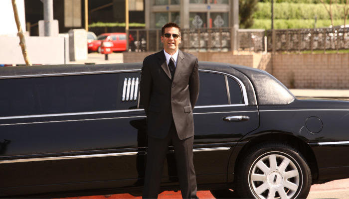 Chauffeur in a tuxedo and sun glasses and Limo in a sunny day 