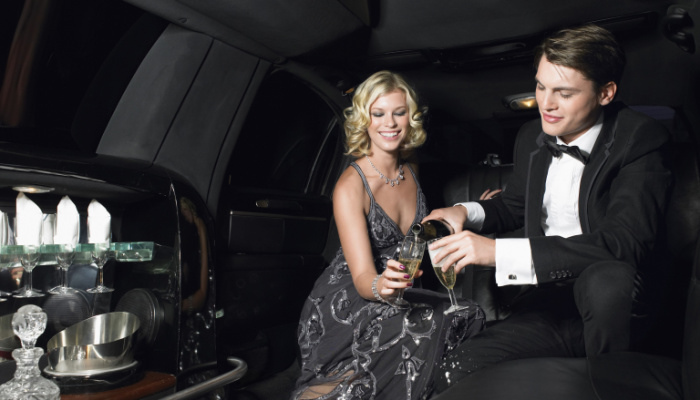 Happy young glamorous couple enjoying champagne in limousine on their date night