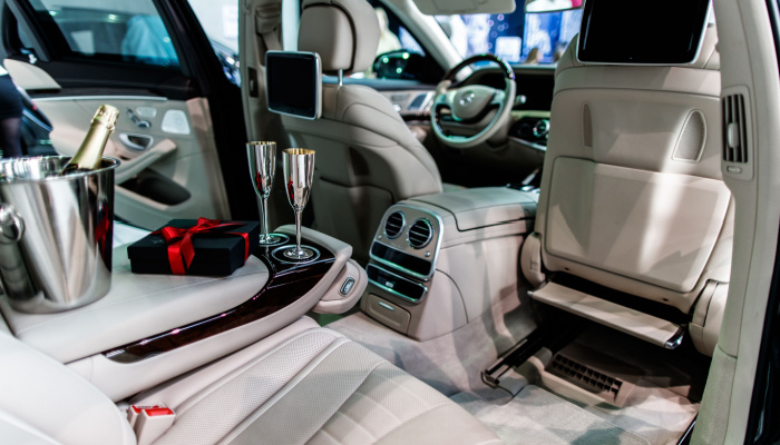 Interior of new luxury car prepared for valentine's day romantic dinner with champagne and gift in white leather interior