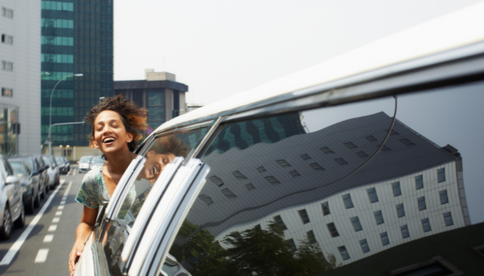 Woman on the window of a limousine car feeling the breeze of the summer air.png