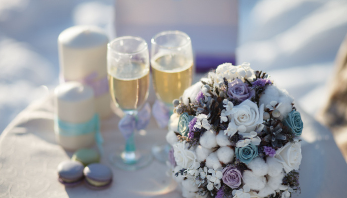 Winter Wedding decoration and theme bouquet of flowers lying on a chair near two wedding glasses and candle