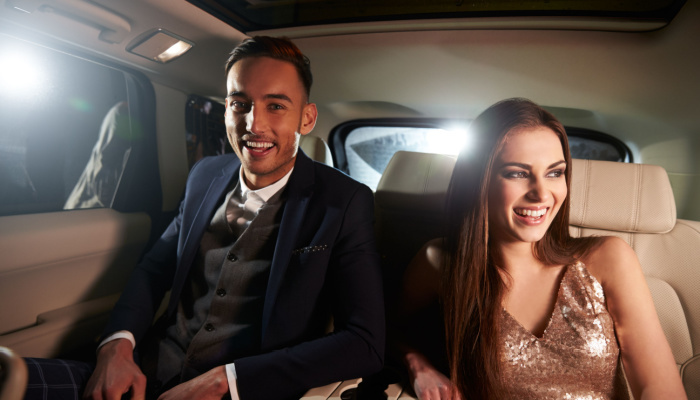 Attractive young couple in their formal attires laughing in the back of a limousine
