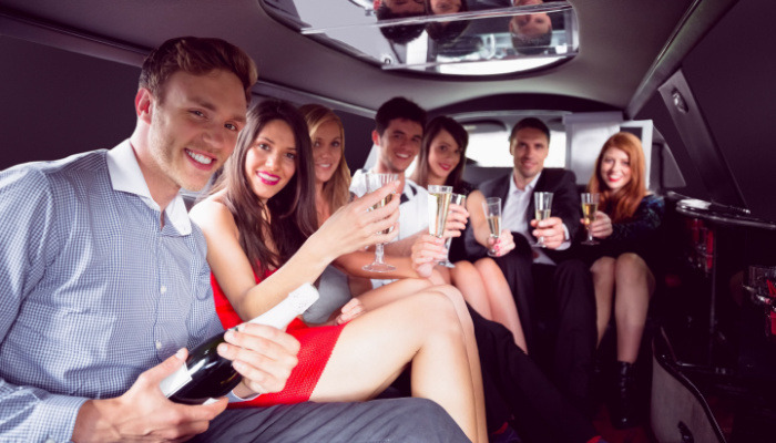 Happy friends drinking wine in limousine on a win tour